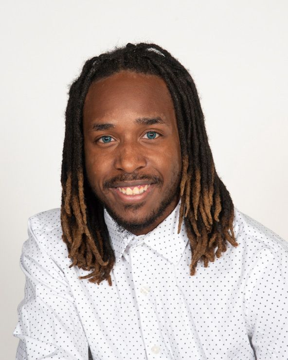 A man with dreadlocks is wearing a white shirt and tie.