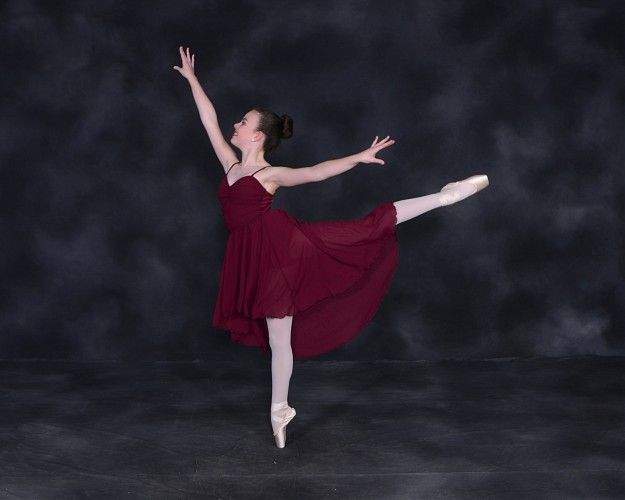 A ballerina in a red dress and pointe shoes is dancing