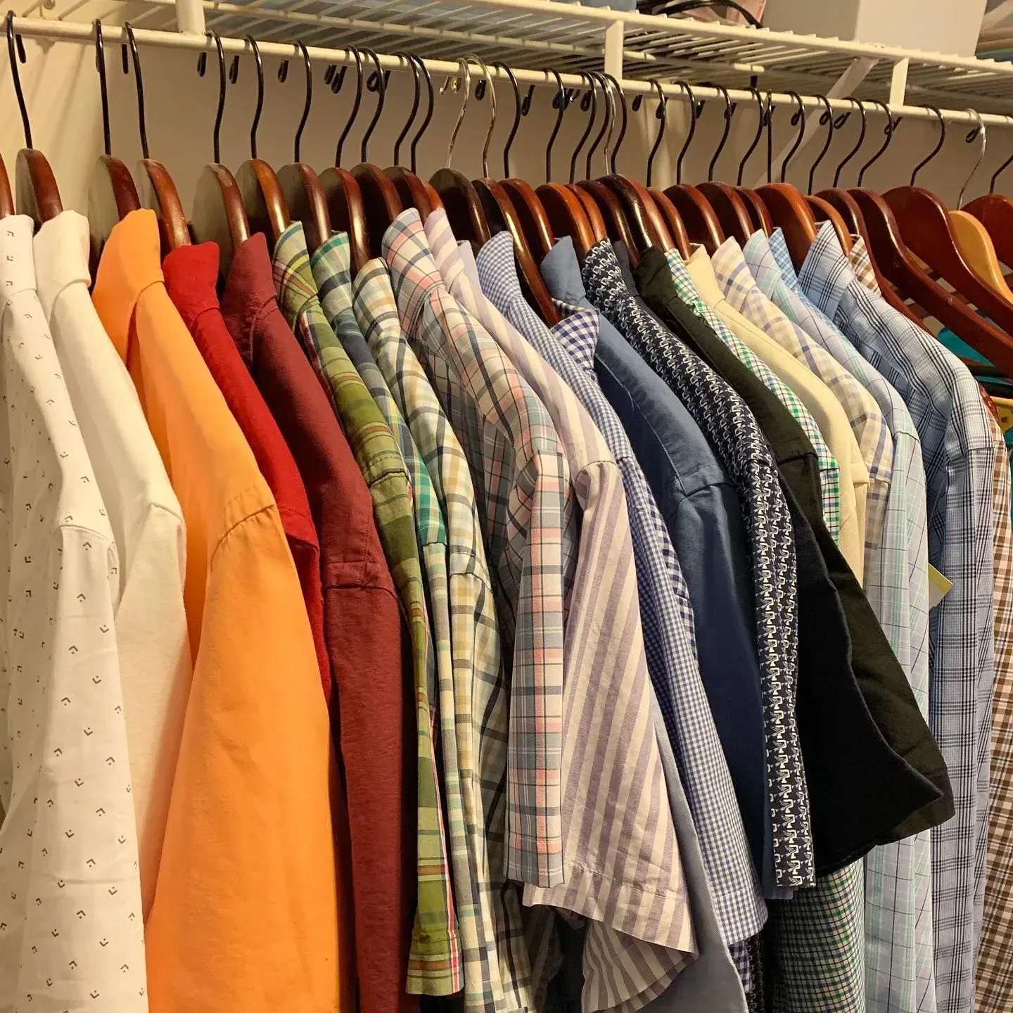 A bunch of shirts are hanging in a closet