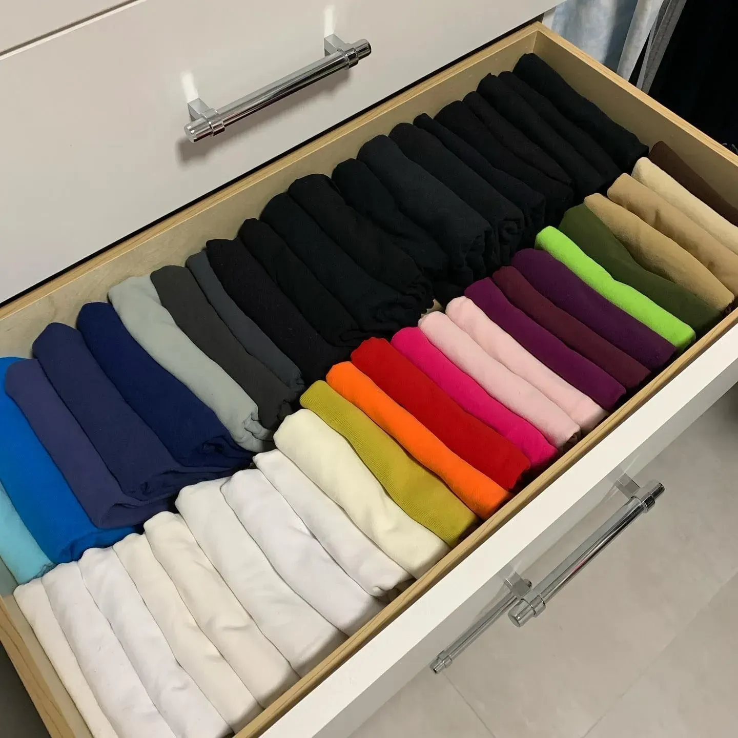 A drawer filled with a variety of folded clothes