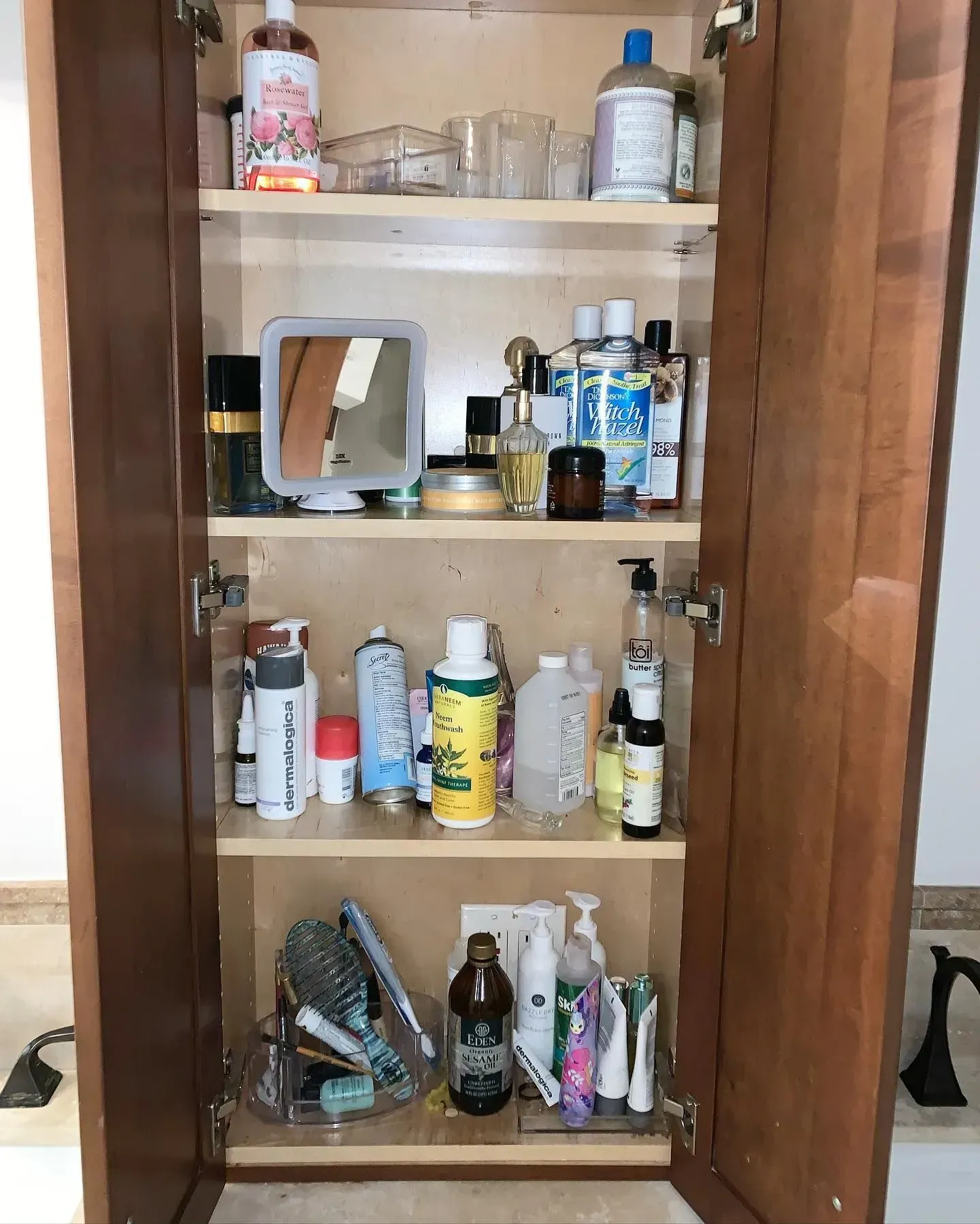 A bathroom cabinet filled with lots of bottles and cosmetics