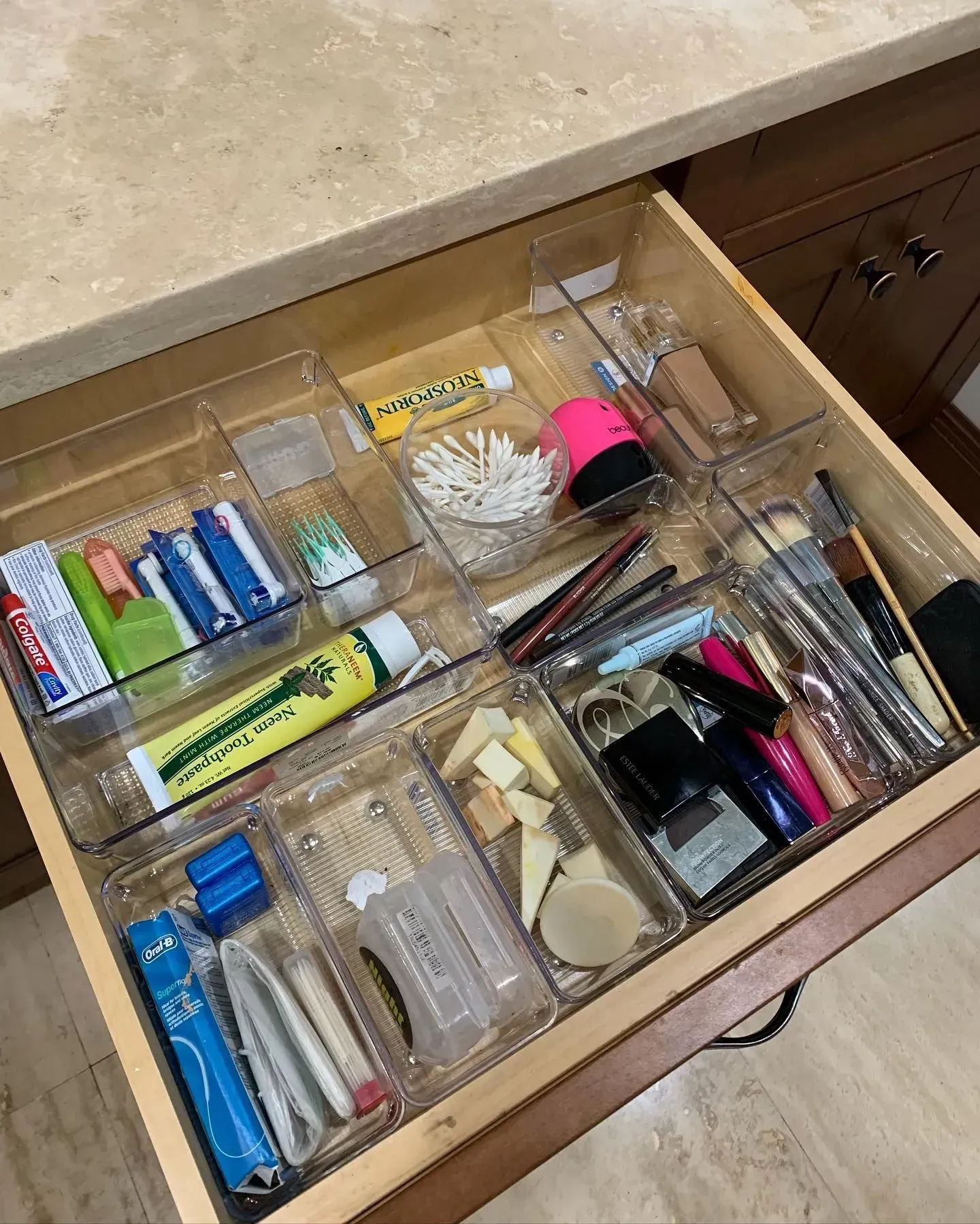 A bathroom drawer filled with toothpaste , toothbrushes , and makeup.