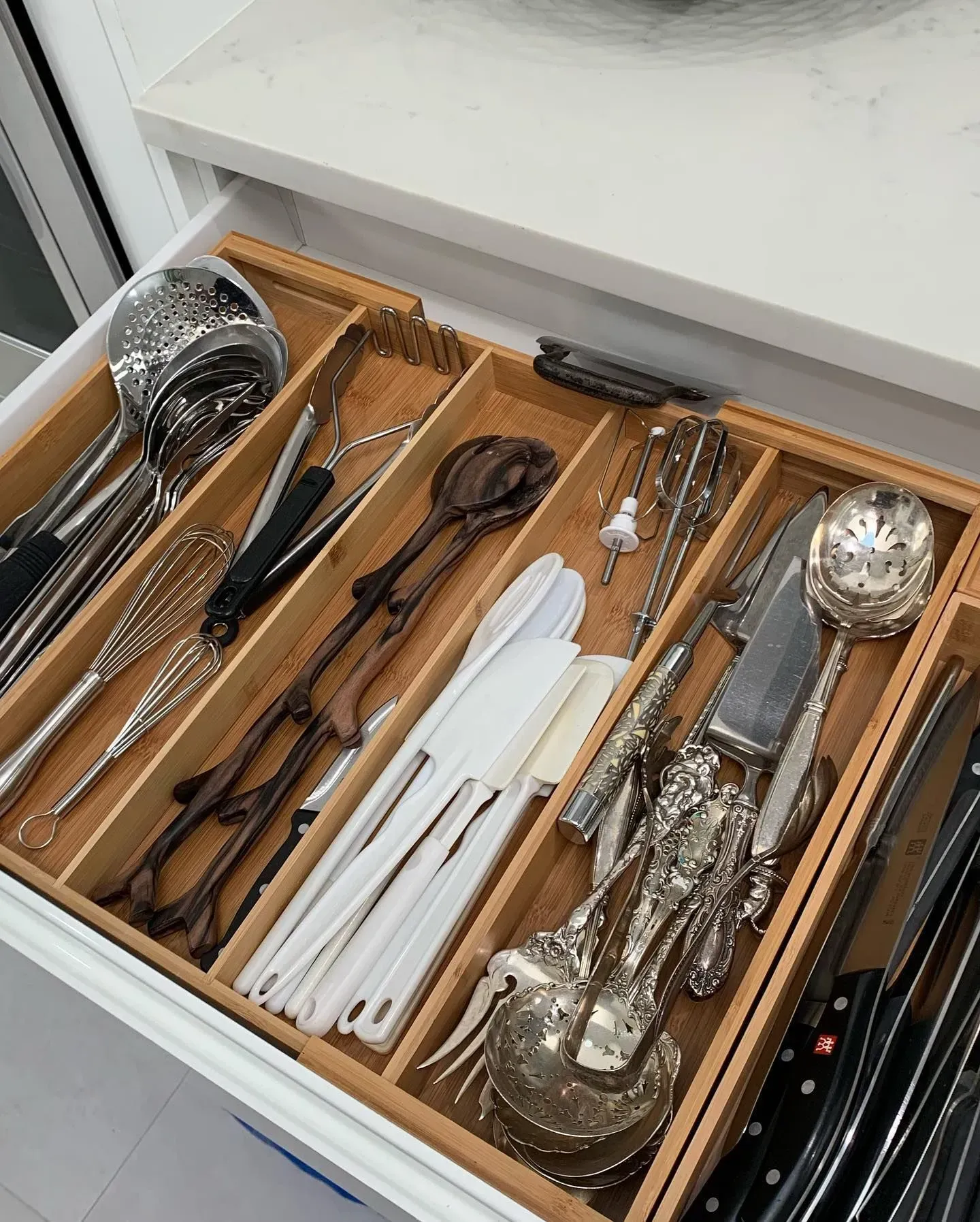 A wooden drawer filled with silverware and utensils.