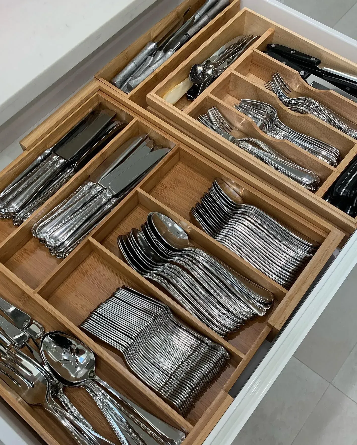 A drawer filled with silverware including knives , forks , spoons and plates.