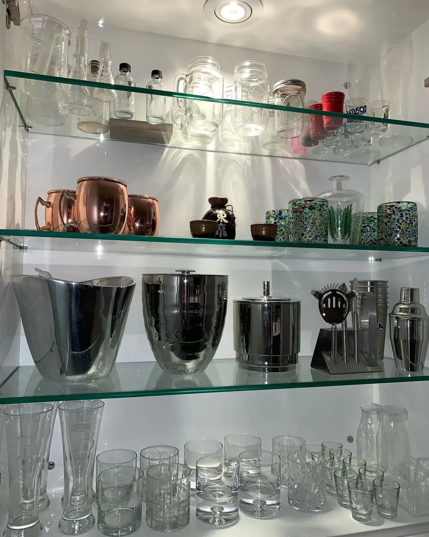 A glass shelf filled with lots of glasses and bottles