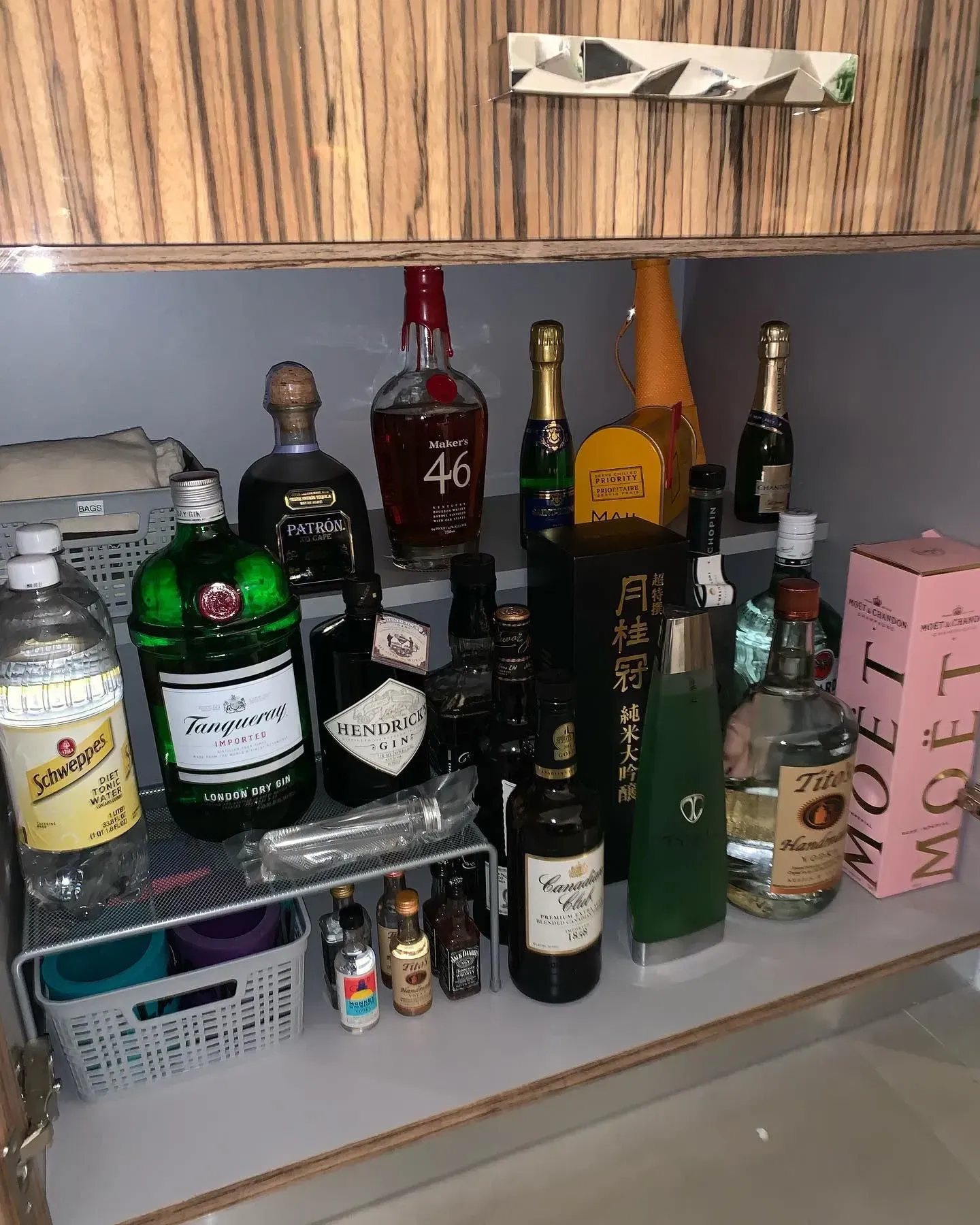 A cabinet filled with bottles of alcohol and a box of moet.