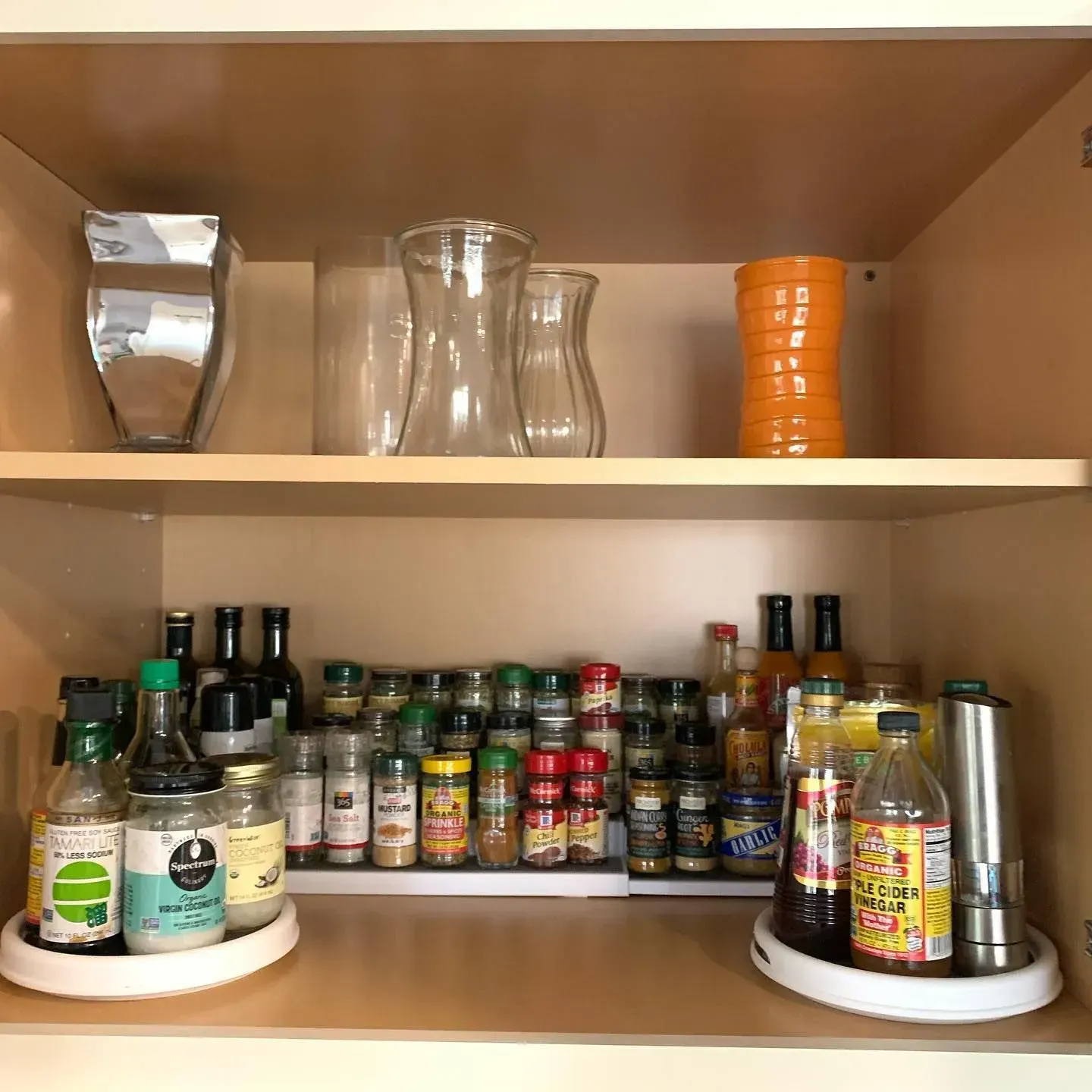 A kitchen cabinet filled with bottles , jars , and vases.