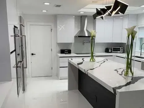 A kitchen with white cabinets and a large island with flowers on it.