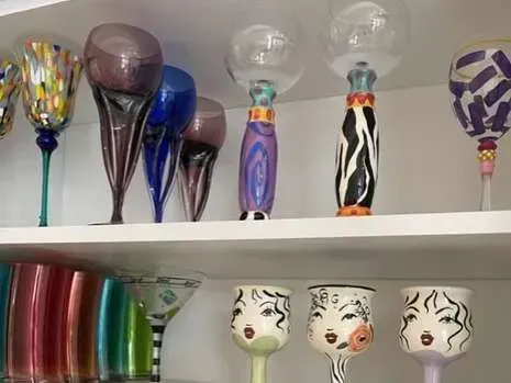 A shelf filled with lots of colorful wine glasses.