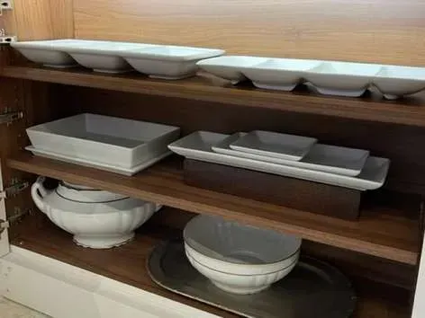 A cabinet filled with bowls , plates , and a tray.