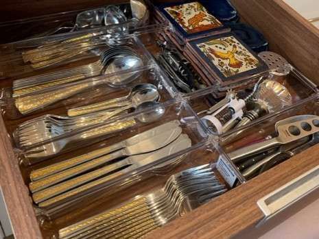 A wooden drawer filled with silverware and utensils.