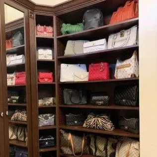 A closet filled with lots of handbags and a mirror.