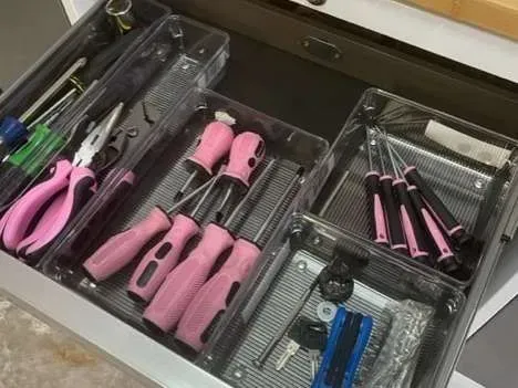A drawer filled with pink tools and keys.