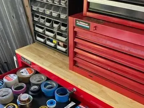 A red toolbox is open to a drawer filled with tape.