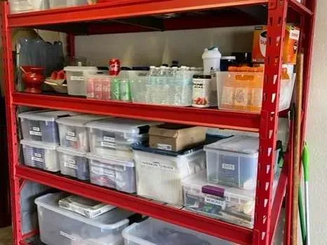 A red shelving unit filled with plastic bins and bottles.