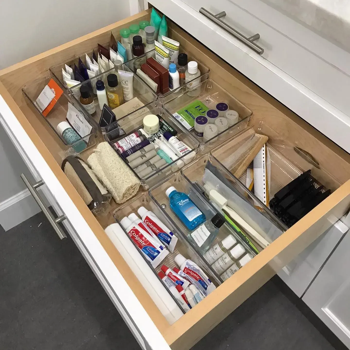 A bathroom drawer filled with toiletries including colgate toothpaste