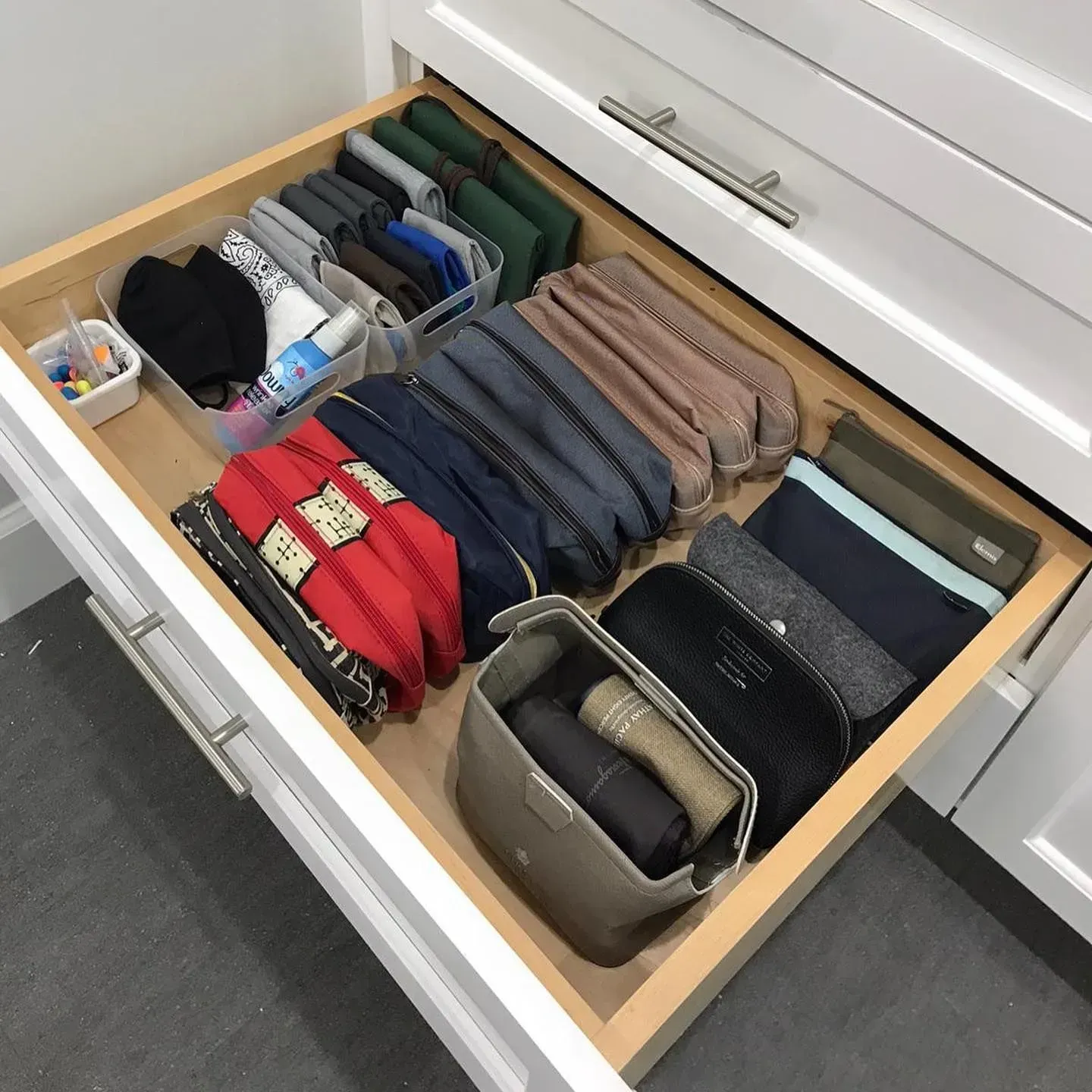 A drawer filled with a variety of items including pencil cases