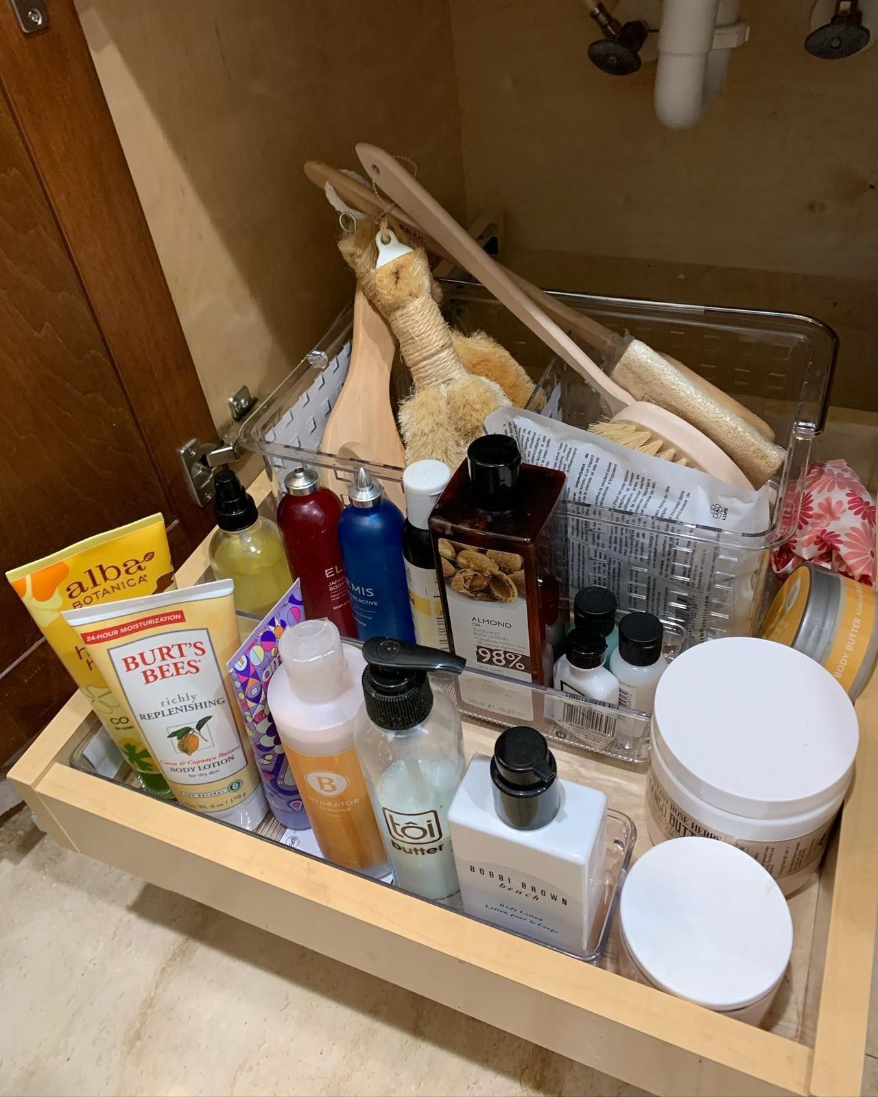 A bathroom drawer filled with bottles , jars , and brushes.