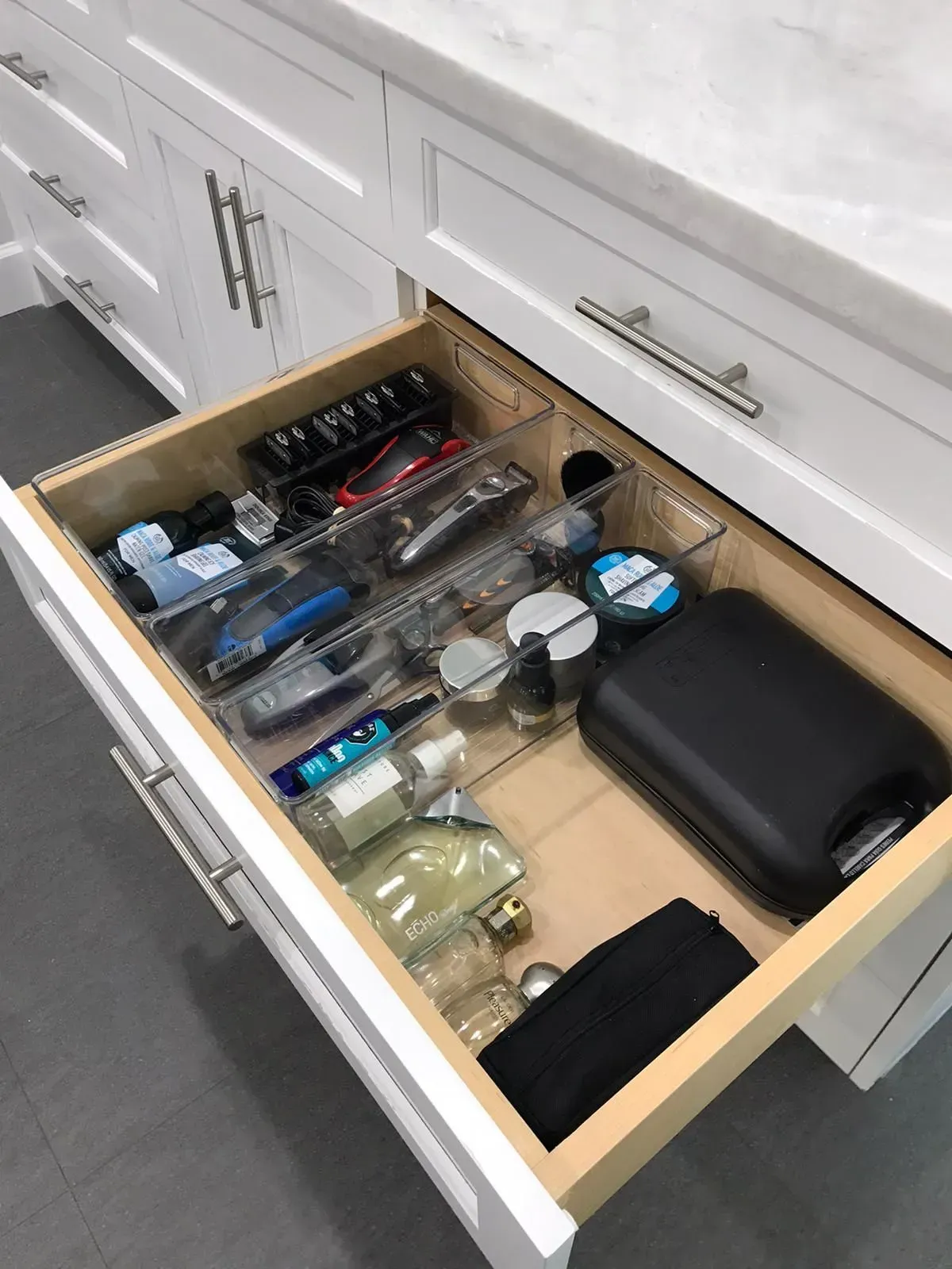A bathroom drawer filled with shaving supplies and a black bag.