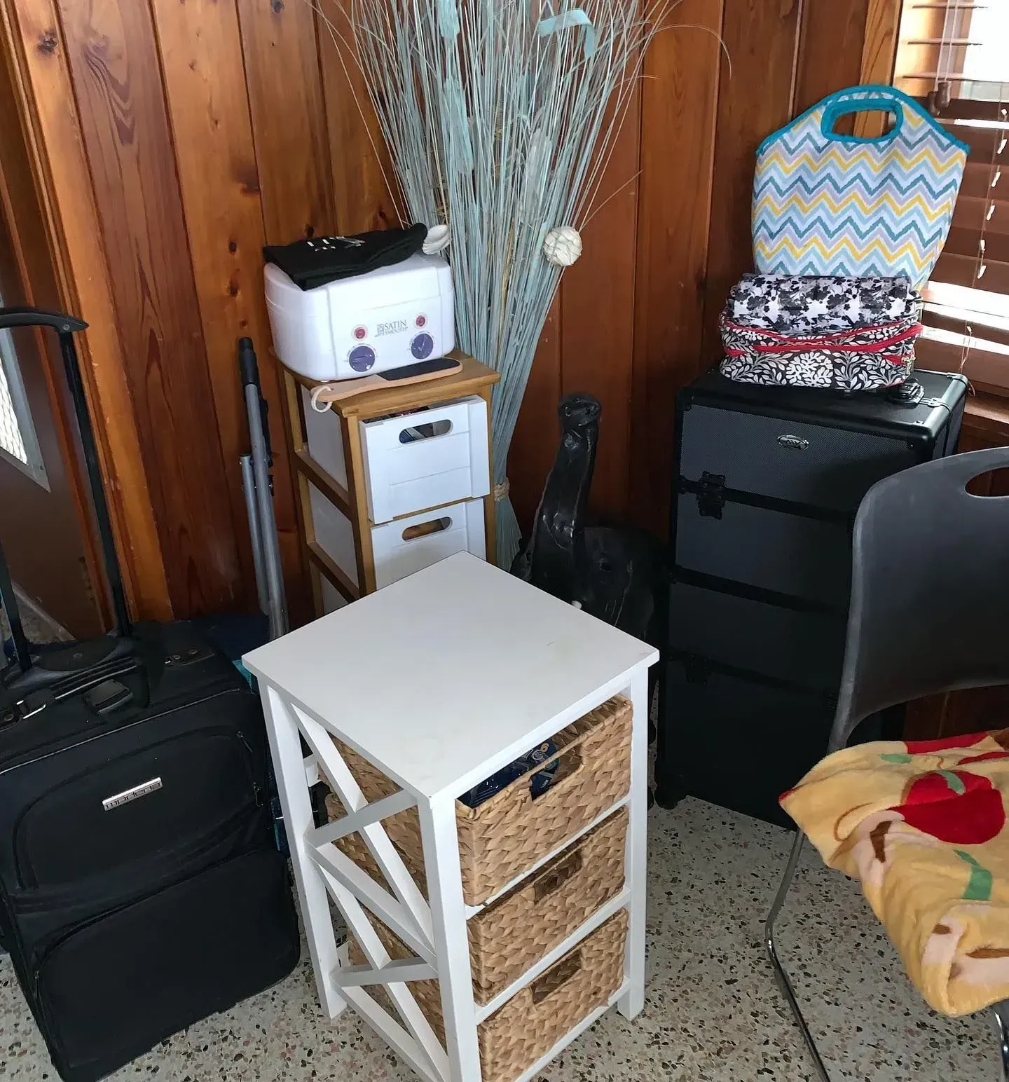 A room filled with luggage , a dresser , a chair and a table.