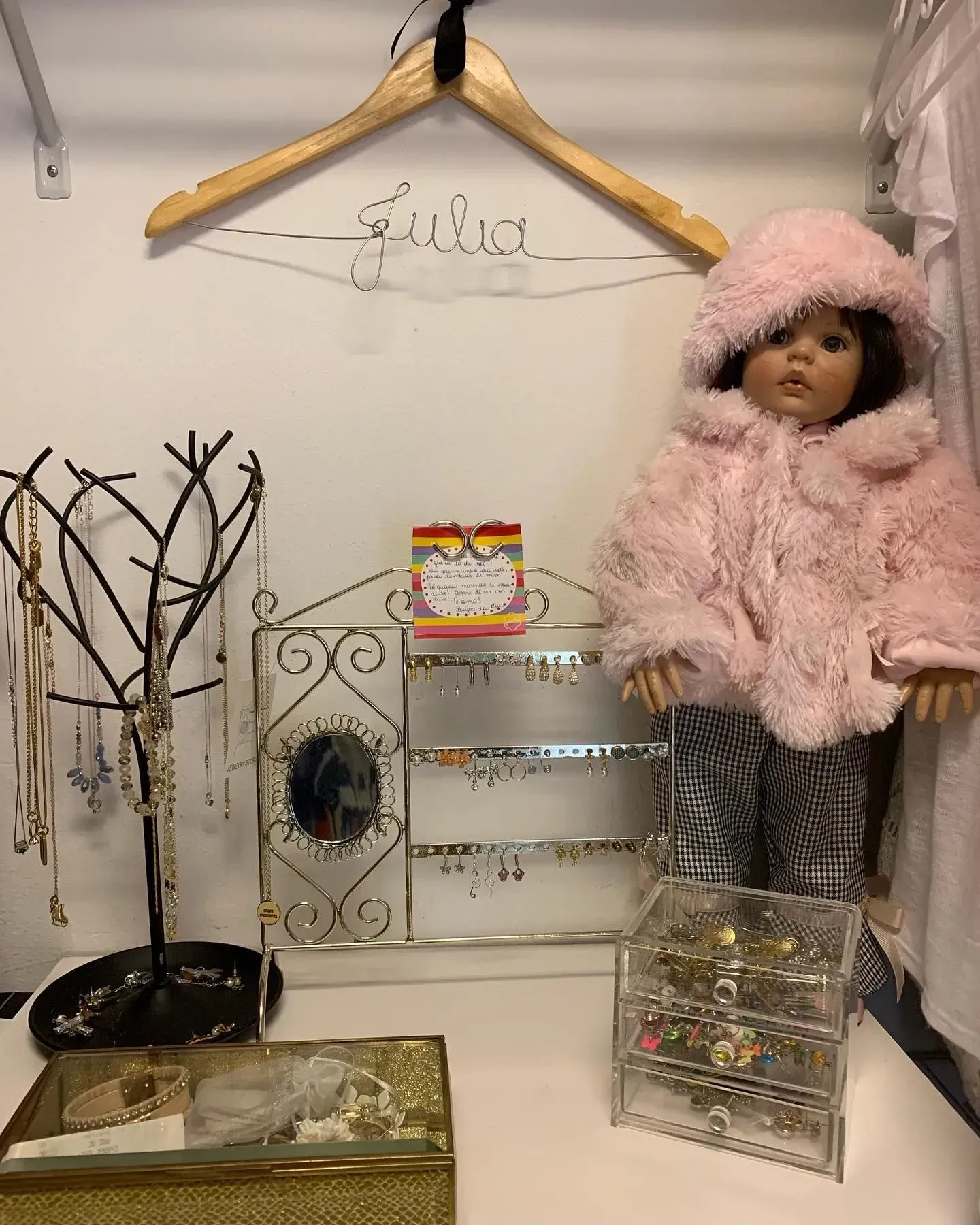 A doll is sitting in a closet next to a jewelry display.