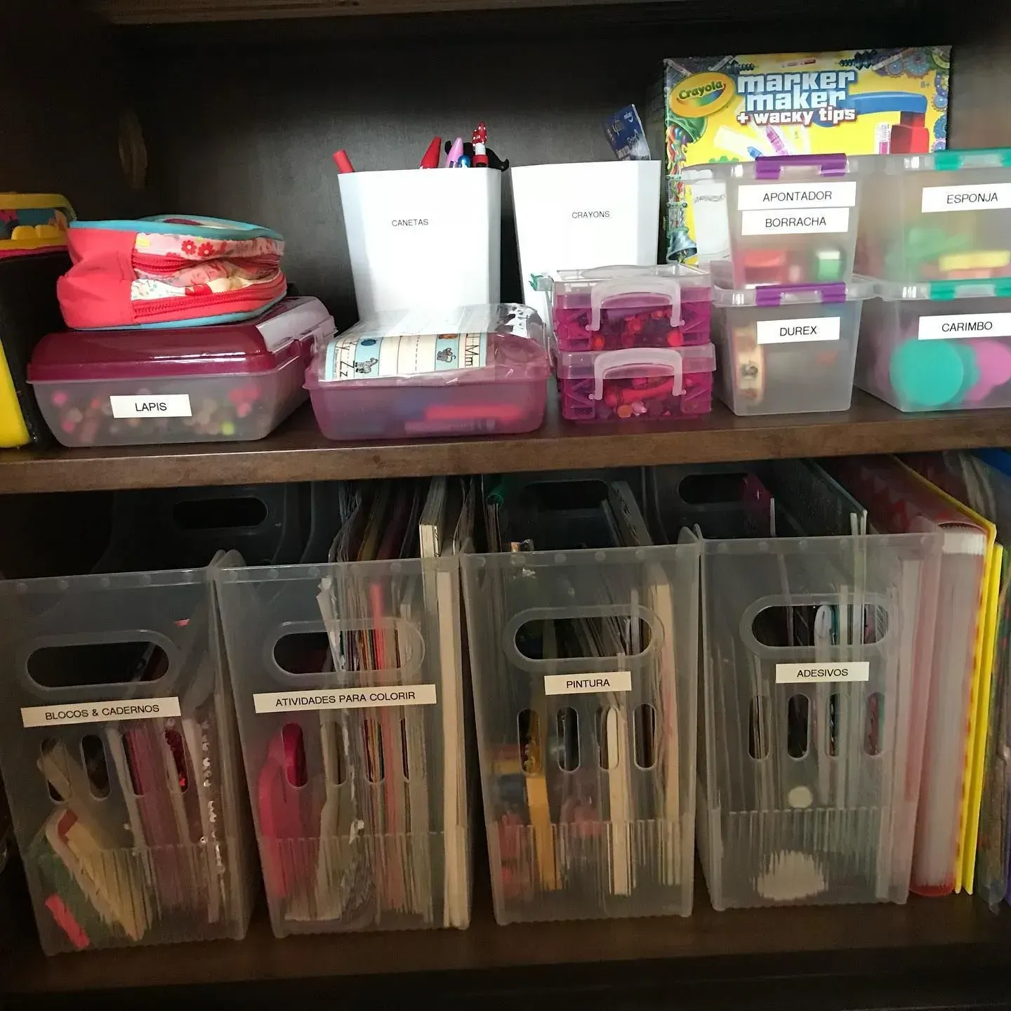 A shelf filled with lots of plastic bins including one that says ' crayola ' on it