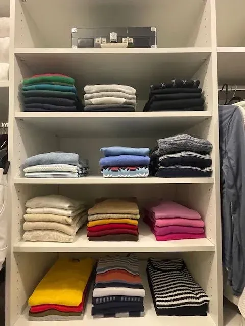 A closet filled with lots of sweaters and shirts