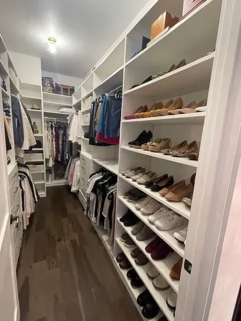 A walk in closet filled with clothes and shoes.