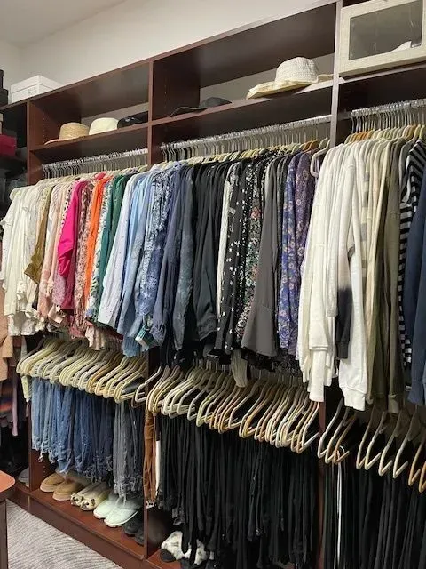 A closet filled with lots of clothes and hats.