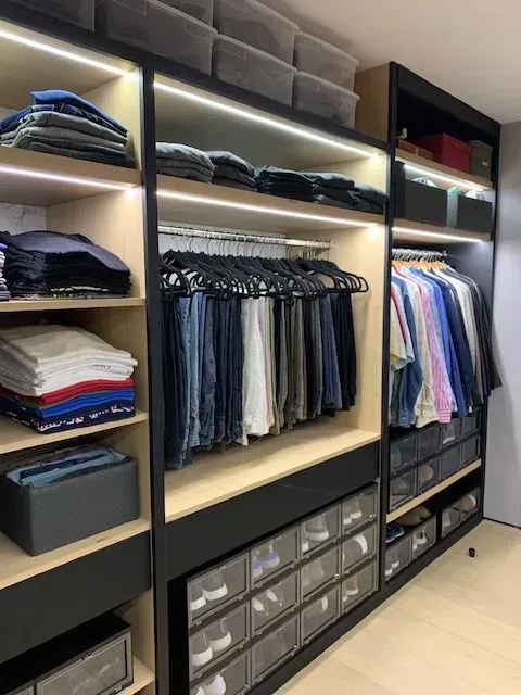 A walk in closet filled with lots of clothes and drawers.