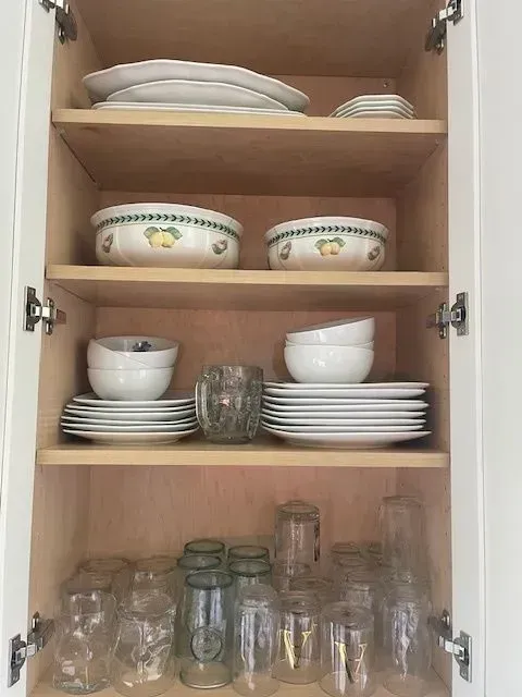 A cabinet filled with plates , bowls , and glasses.