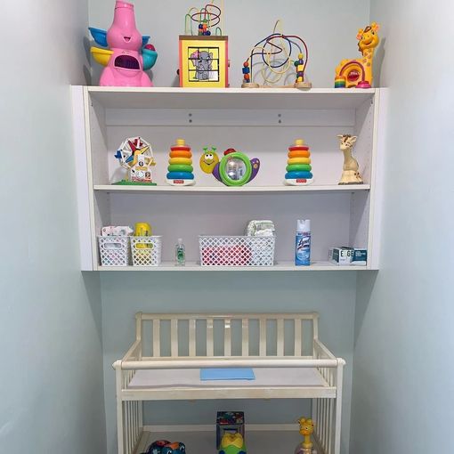 A room with a changing table and shelves full of toys