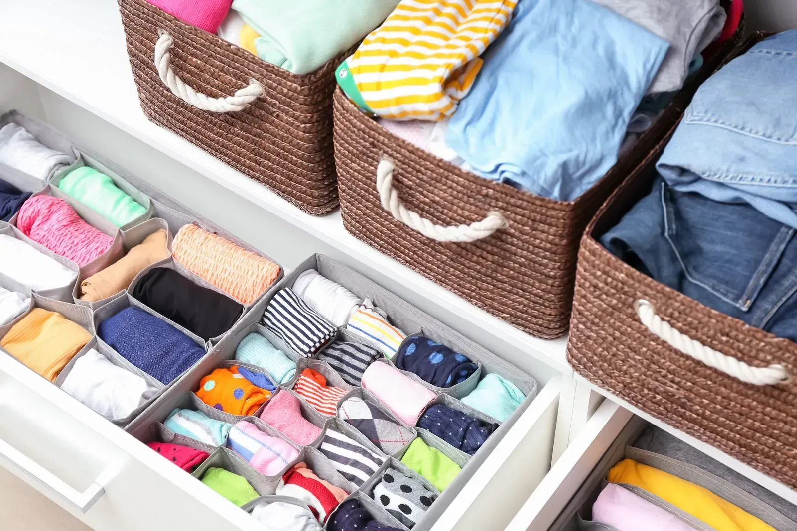 A closet filled with lots of clothes and wicker baskets.