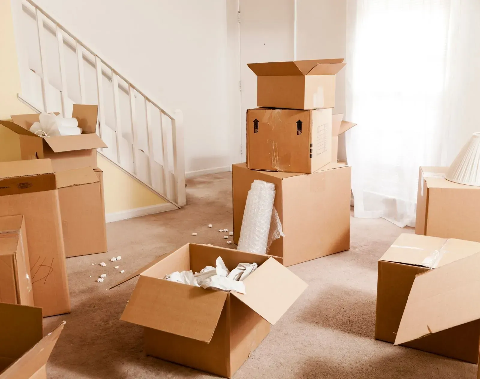A living room filled with cardboard boxes and a staircase.