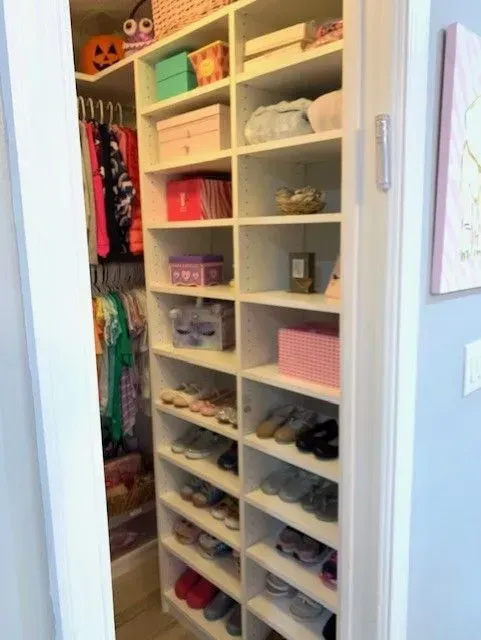 A walk in closet filled with lots of shoes and clothes.