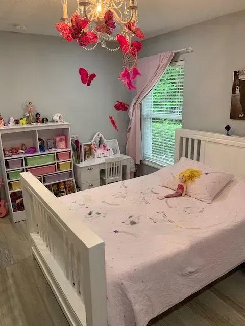 A bedroom with a bed and a chandelier with butterflies hanging from it