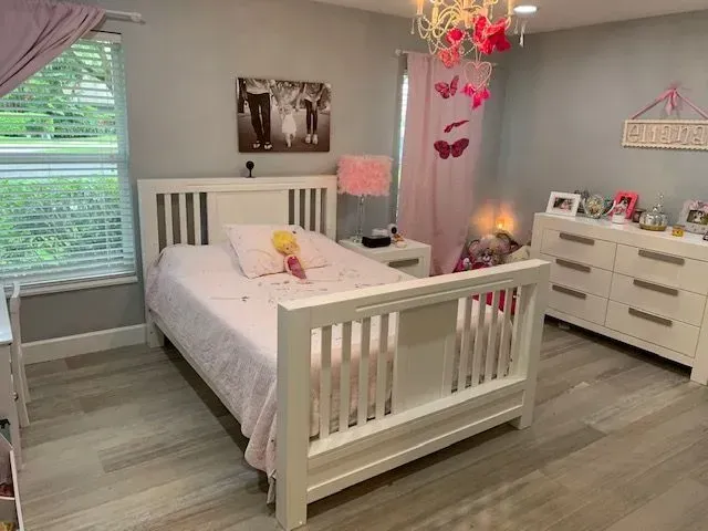 A bedroom with a bed , dresser , nightstand and window.