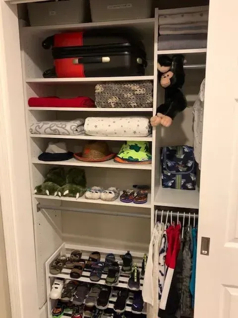A closet filled with clothes and a stuffed monkey