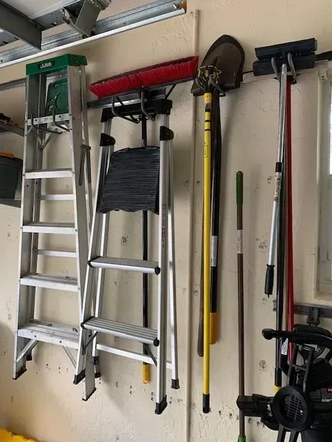 A bunch of tools are hanging on a wall in a garage.