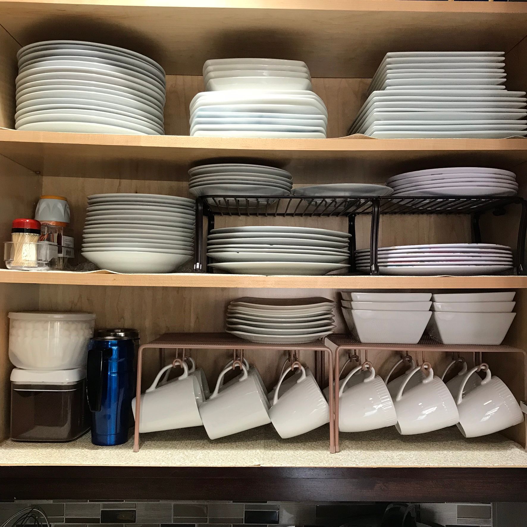 A kitchen cabinet filled with plates bowls and cups