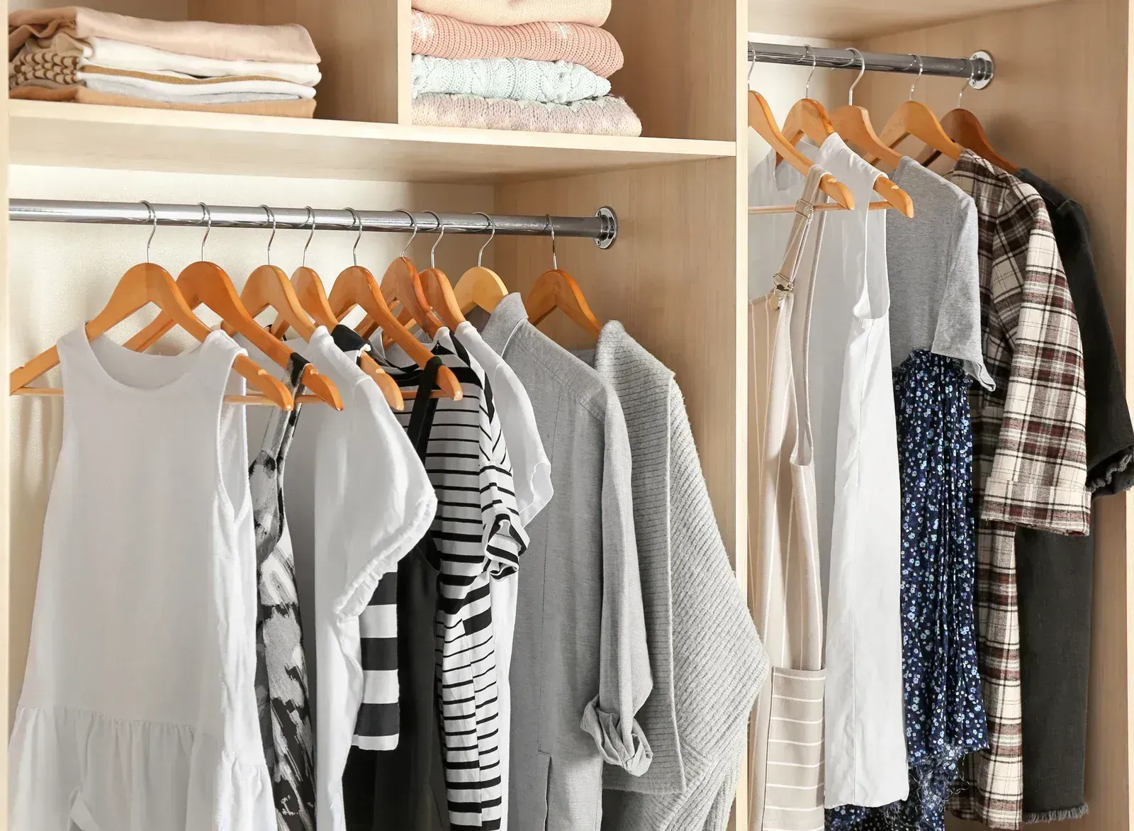 A closet filled with clothes and a stack of towels.