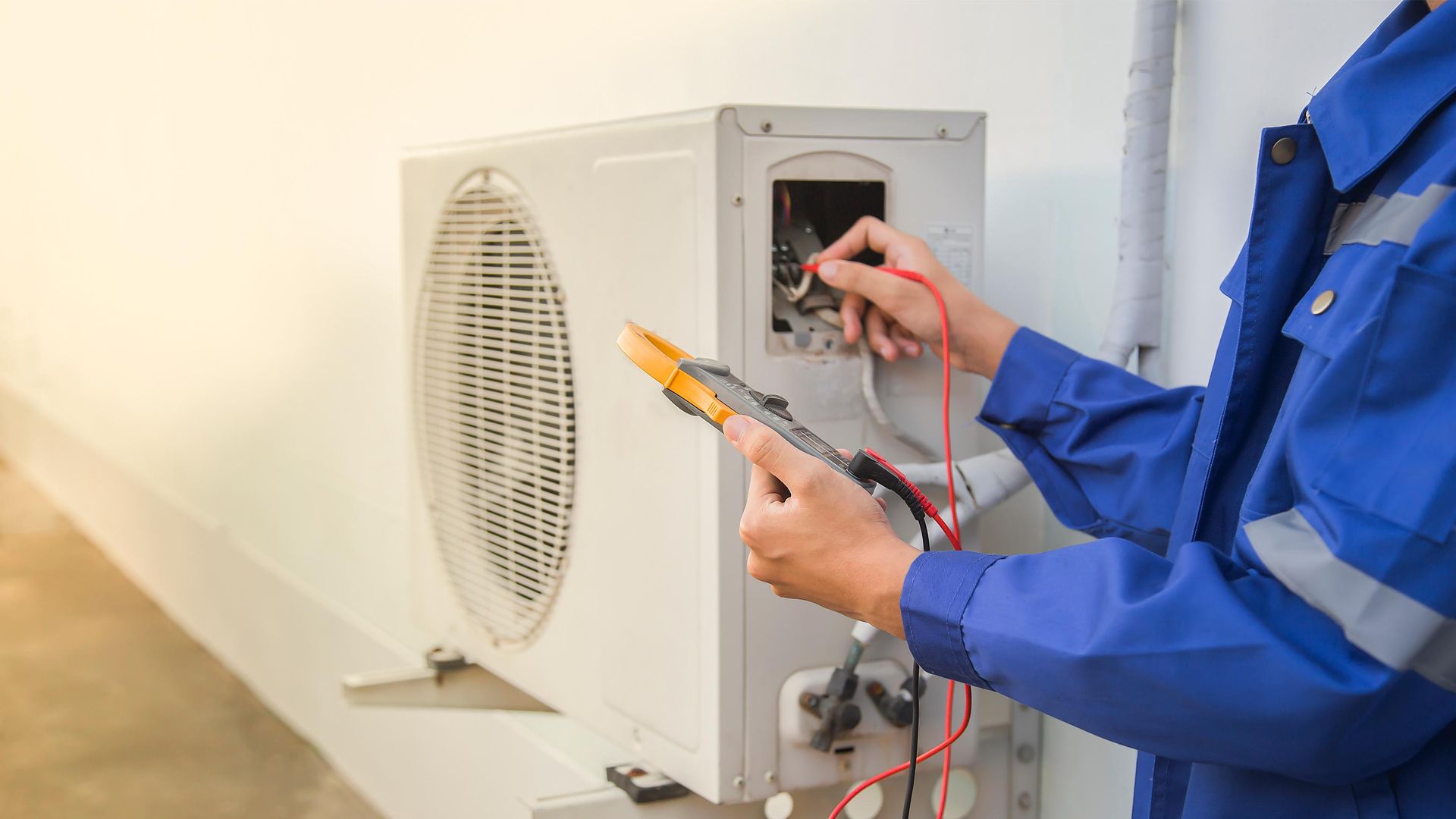 a man in a blue uniform is working on an air conditioner .