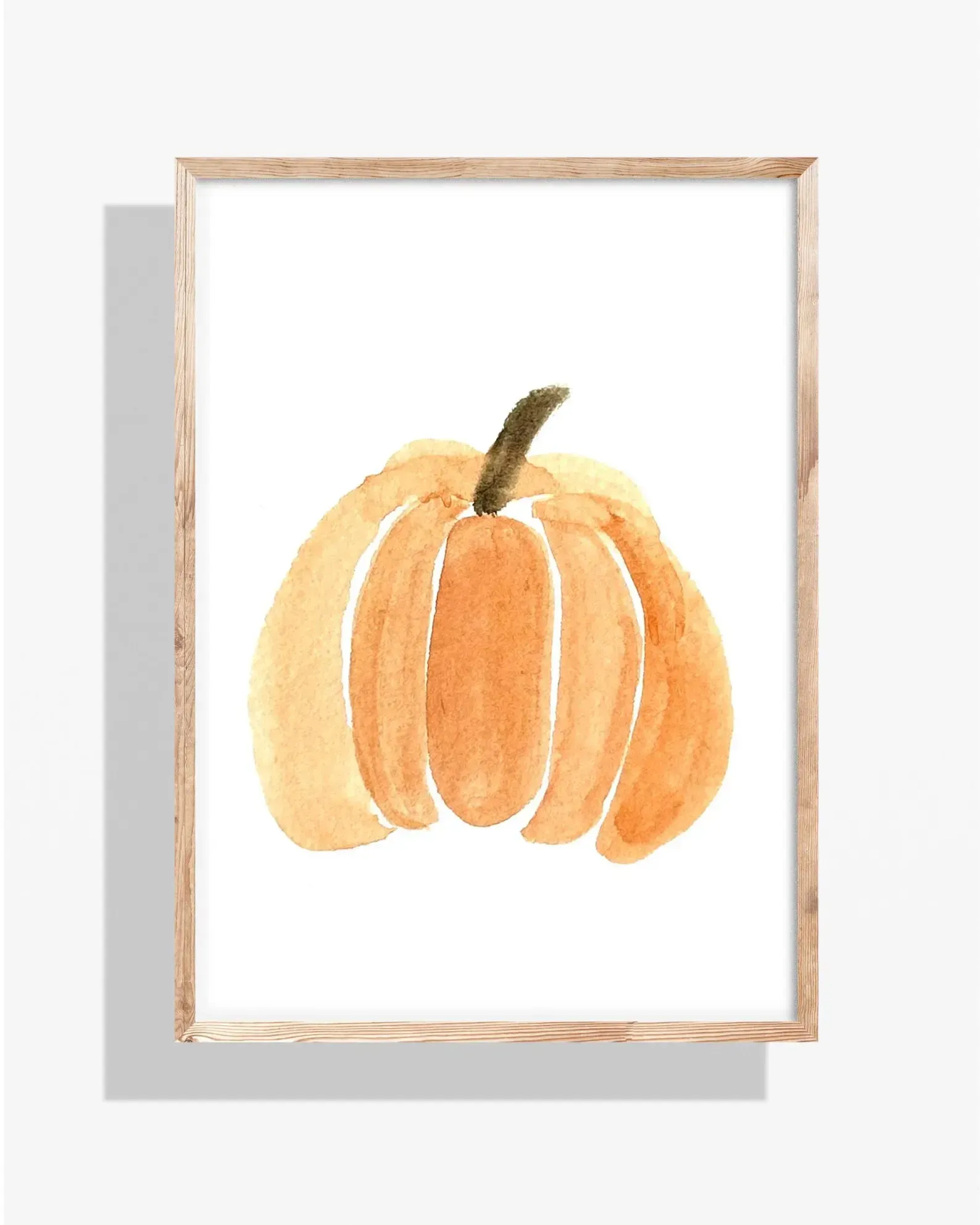 Watercolor painting of an orange pumpkin with a green stem, framed in a light wooden frame, against a white background.