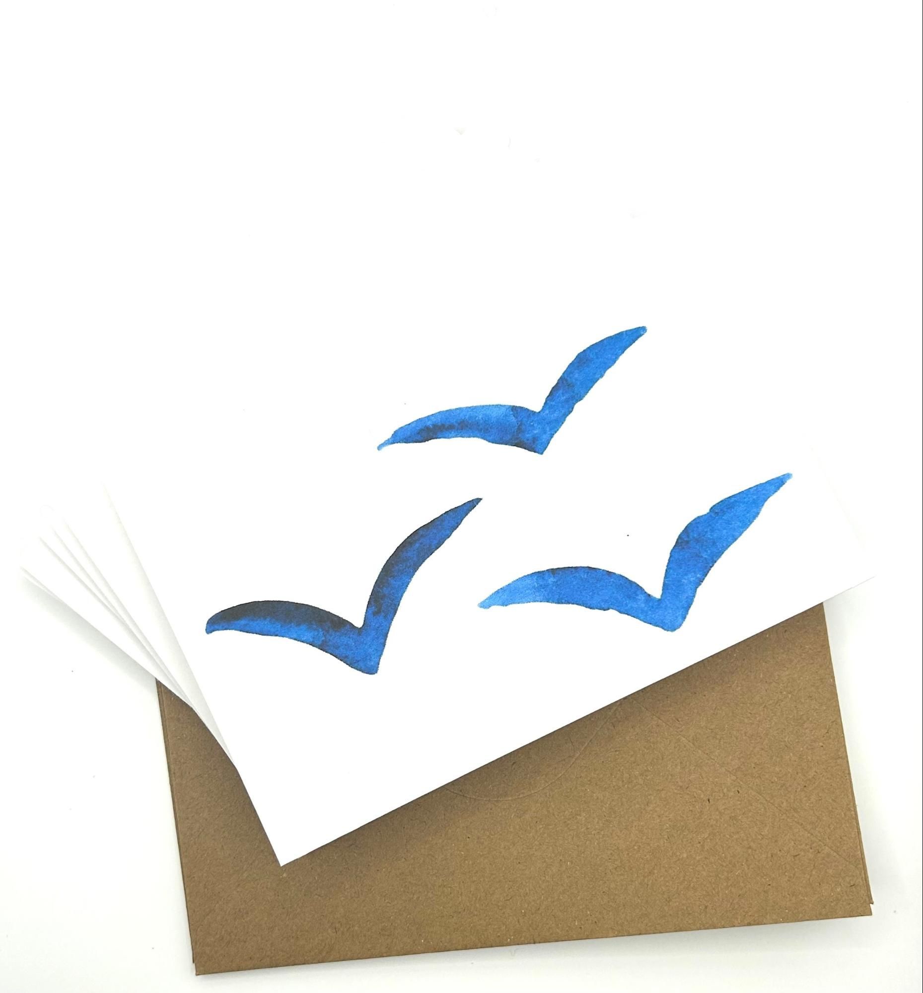 Three blue watercolor seagulls on a white card, sitting on a brown envelope.