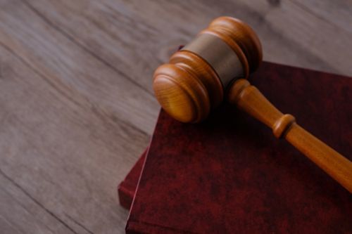A wooden judge's gavel is sitting on top of a red book.
