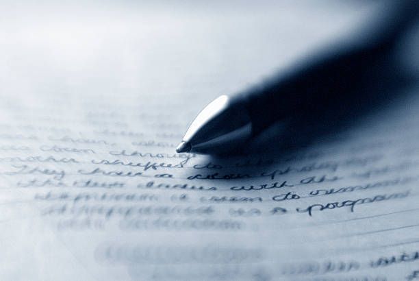 A person is writing on a piece of paper with a pen.