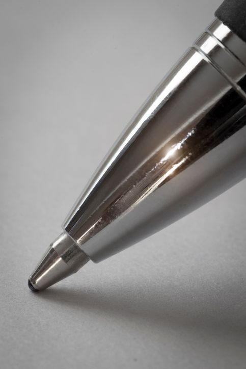 A close up of the tip of a pen on a gray surface.