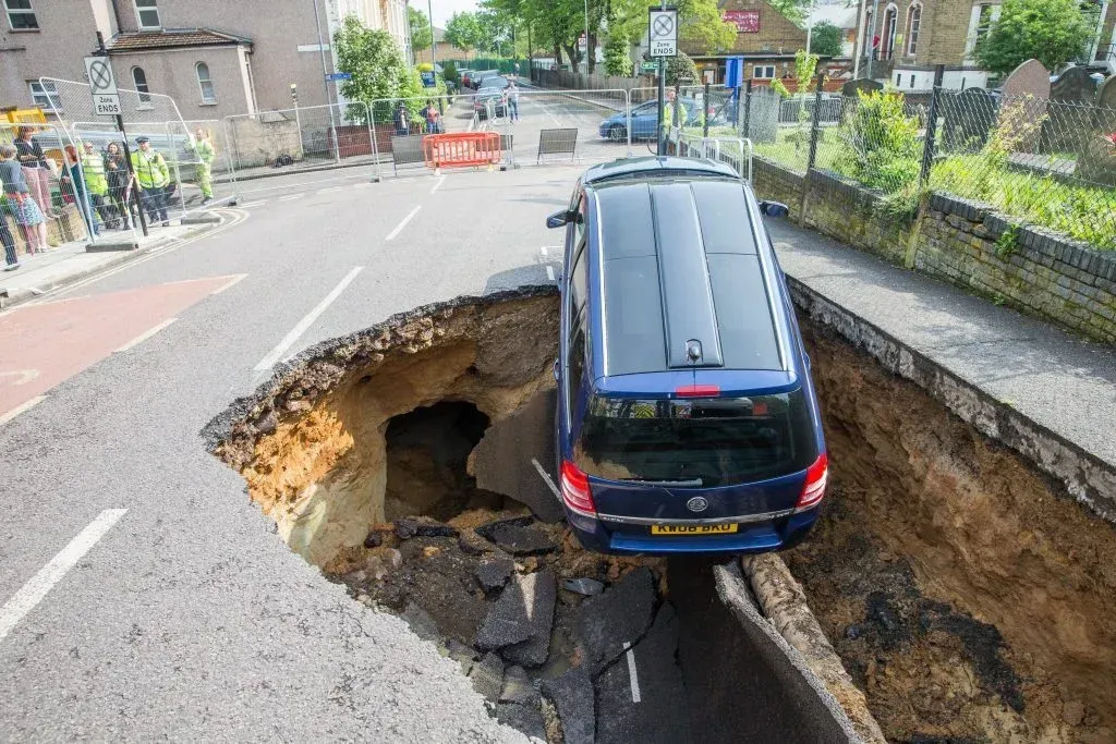 A car is stuck in a hole in the road.