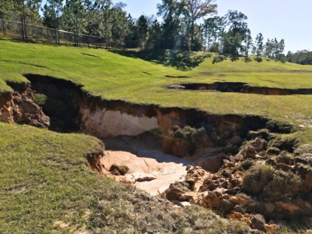 Erosion on a grassy hill, revealing sandy soil underneath.
