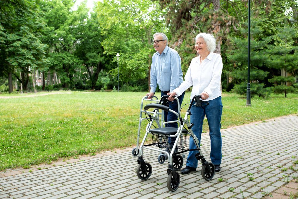 Elderly Couple Walking With a Walker on a Brick Path in a Park — Elder Care Connect in Highland Park, QLD